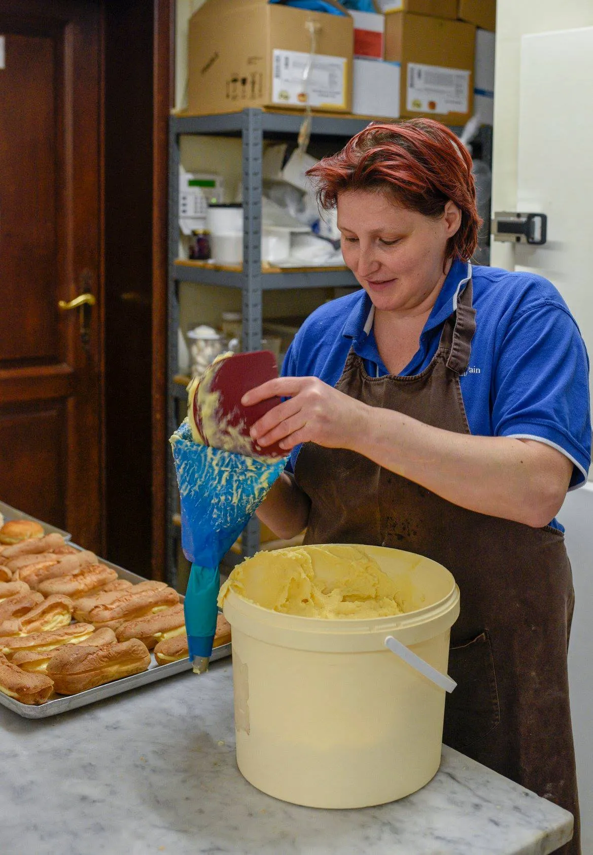 Cathy vult éclairs met een spuitzak in het atelier