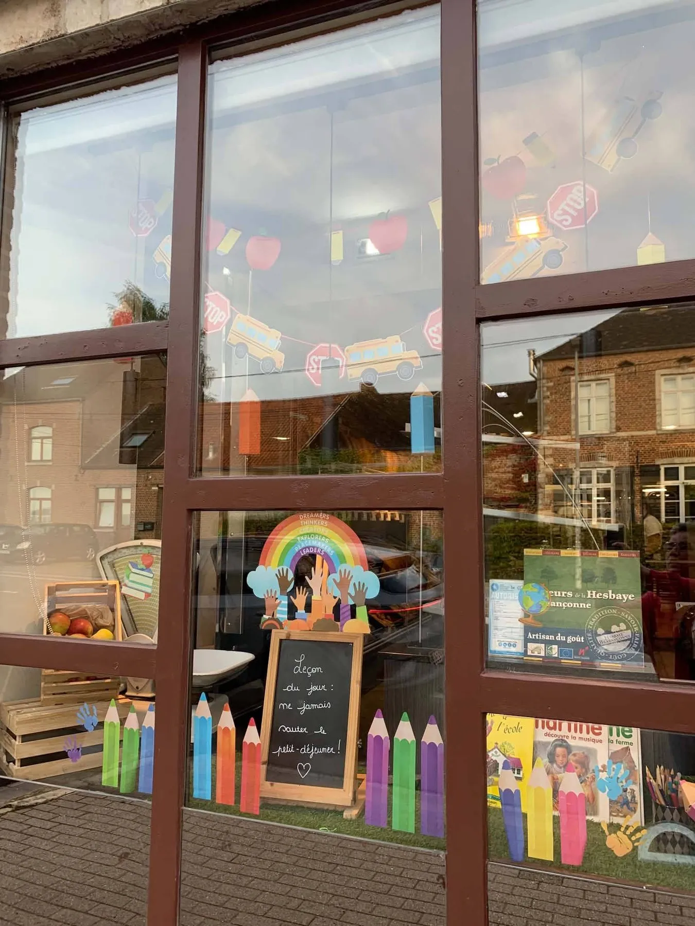 Etalage voor het nieuwe schooljaar met reuzenpotloden en een regenboog